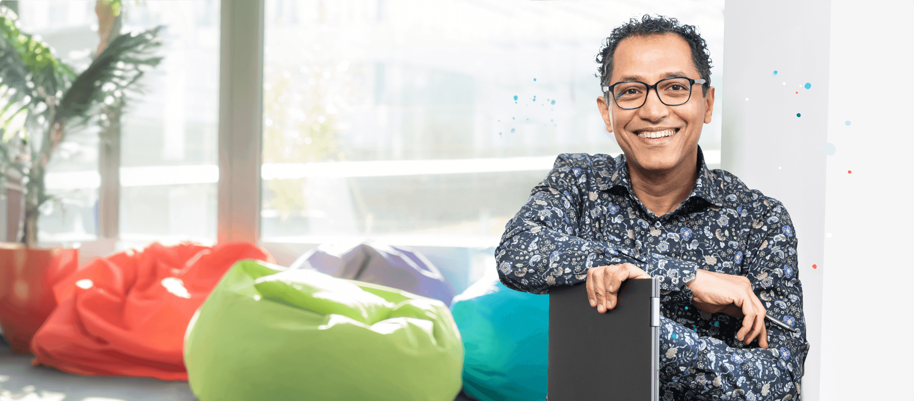 Person mit Notebook vor bunten Kissen